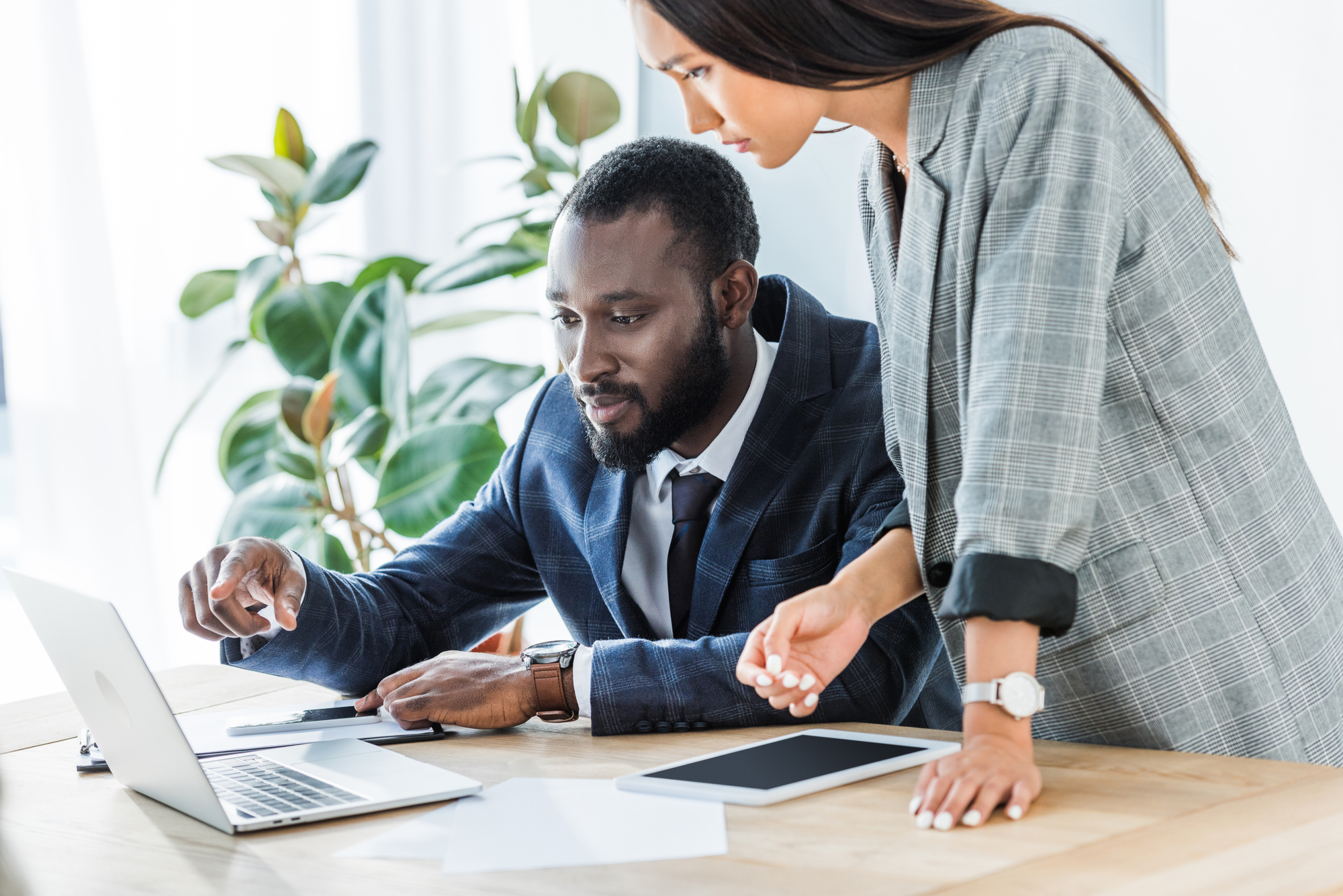 African american businessman and asian businesswoman looking at laptop in office