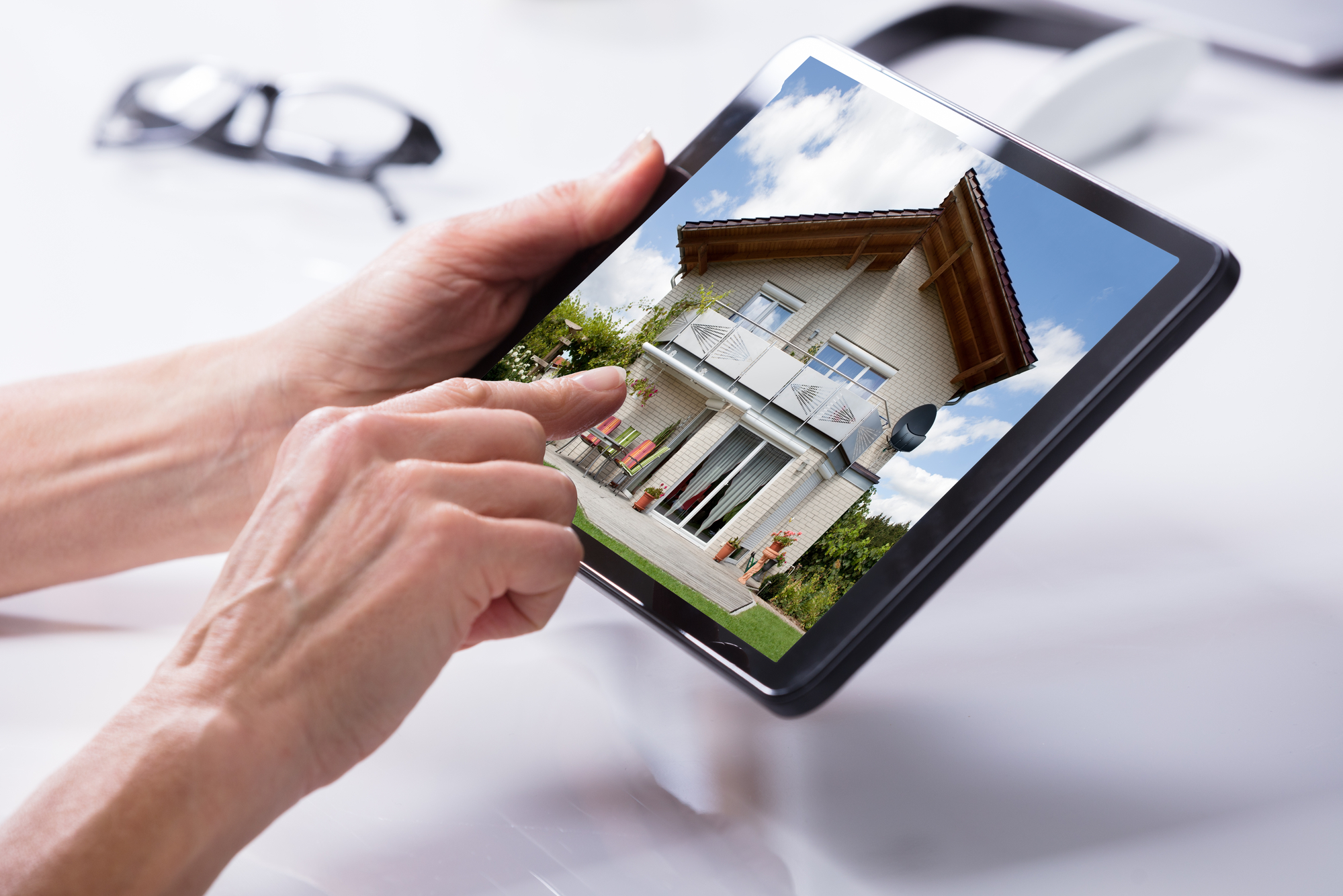 Close-up Of A Persons Hand Holding Digital Tablet With House On Screen