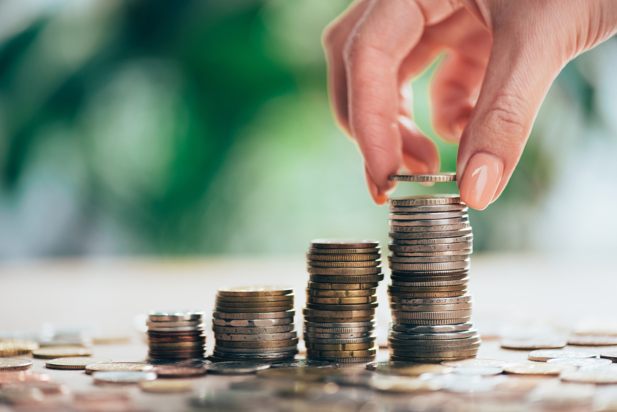 Cropped shot of person putting coin on stacked coins