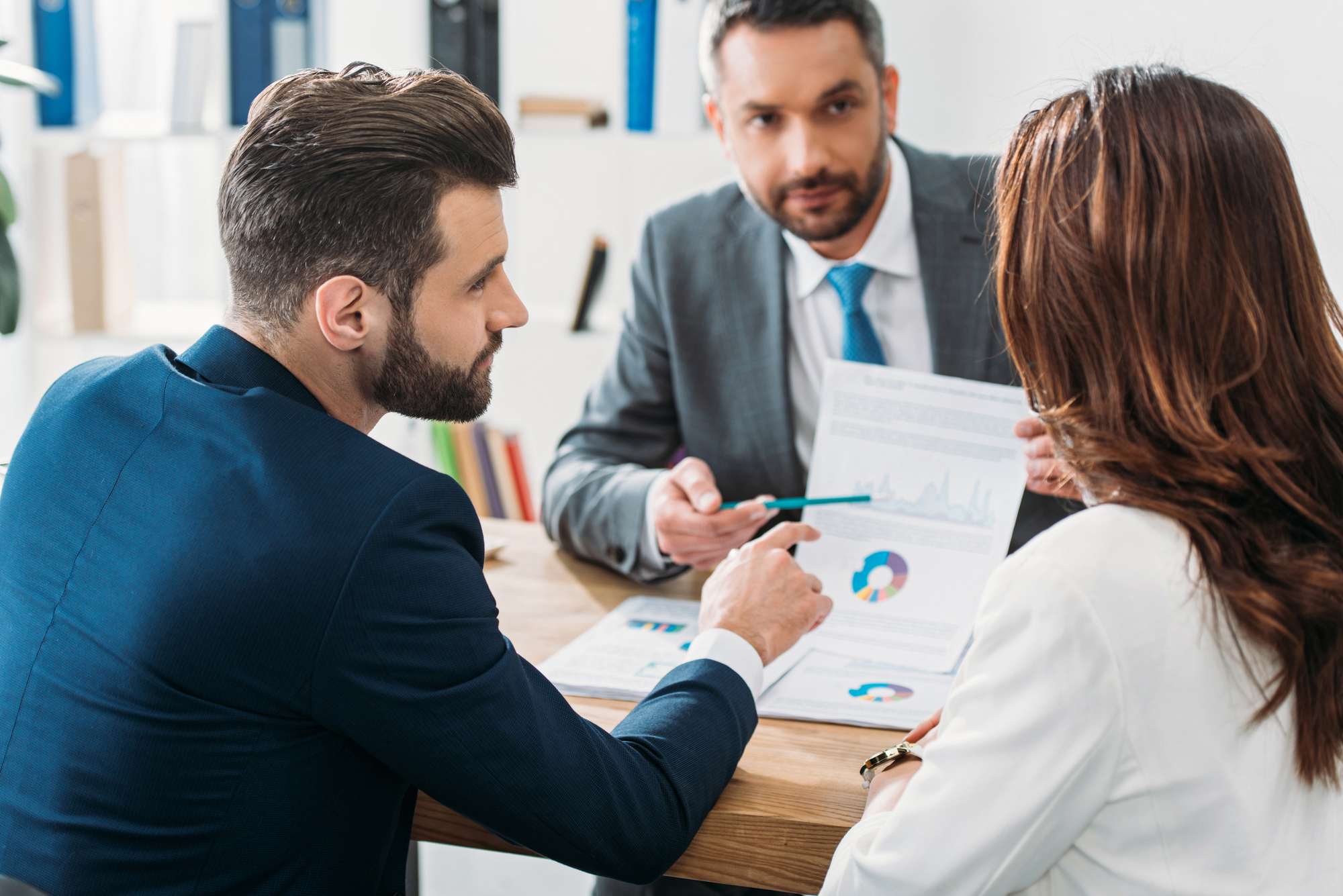 Selective focus of investor in suit pointing with finger at document at workspace-1